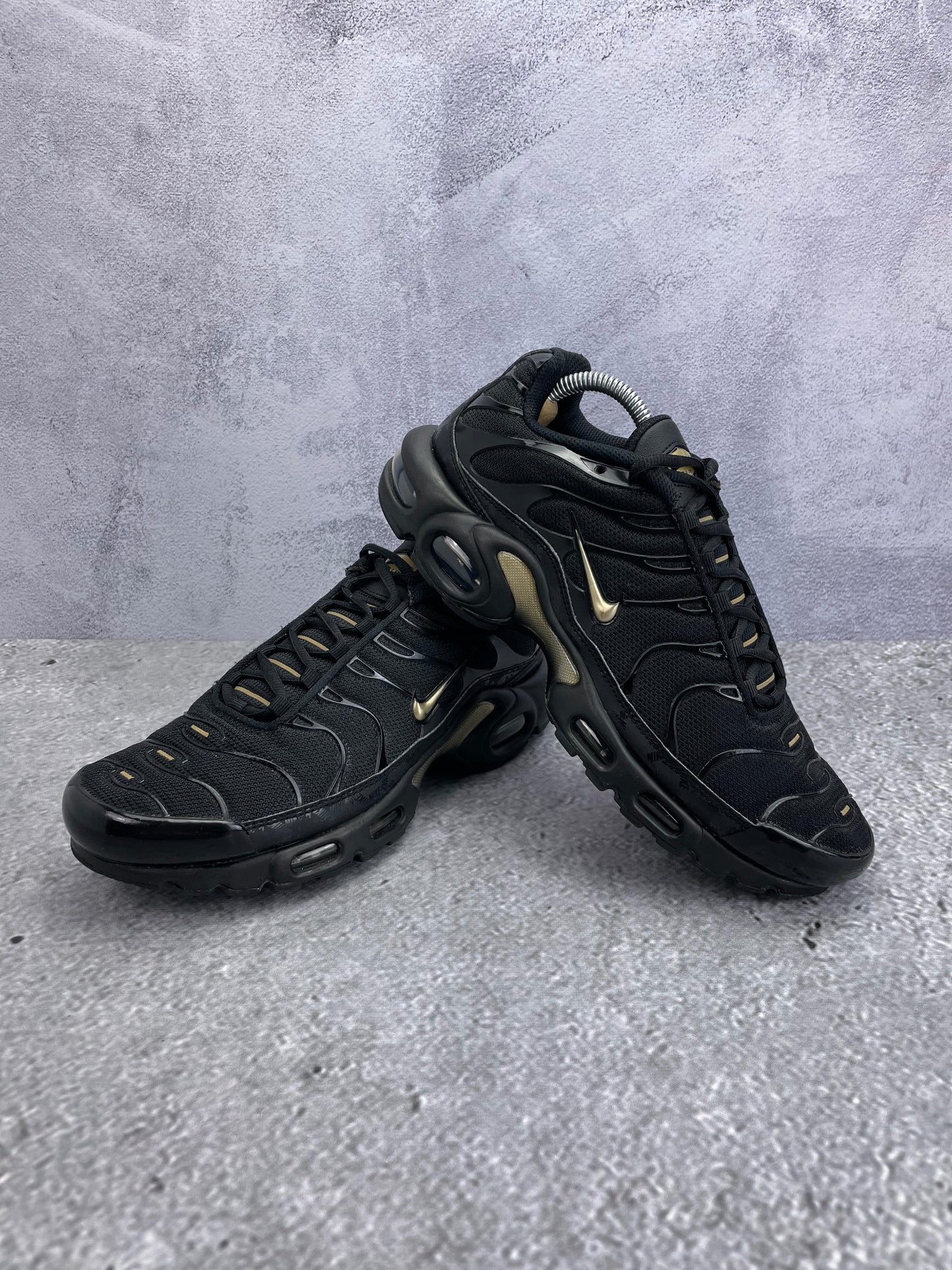 Nike Air Max Plus Black Metallic Gold - buty sportowe, para butów, widok z boku na tle studyjnym