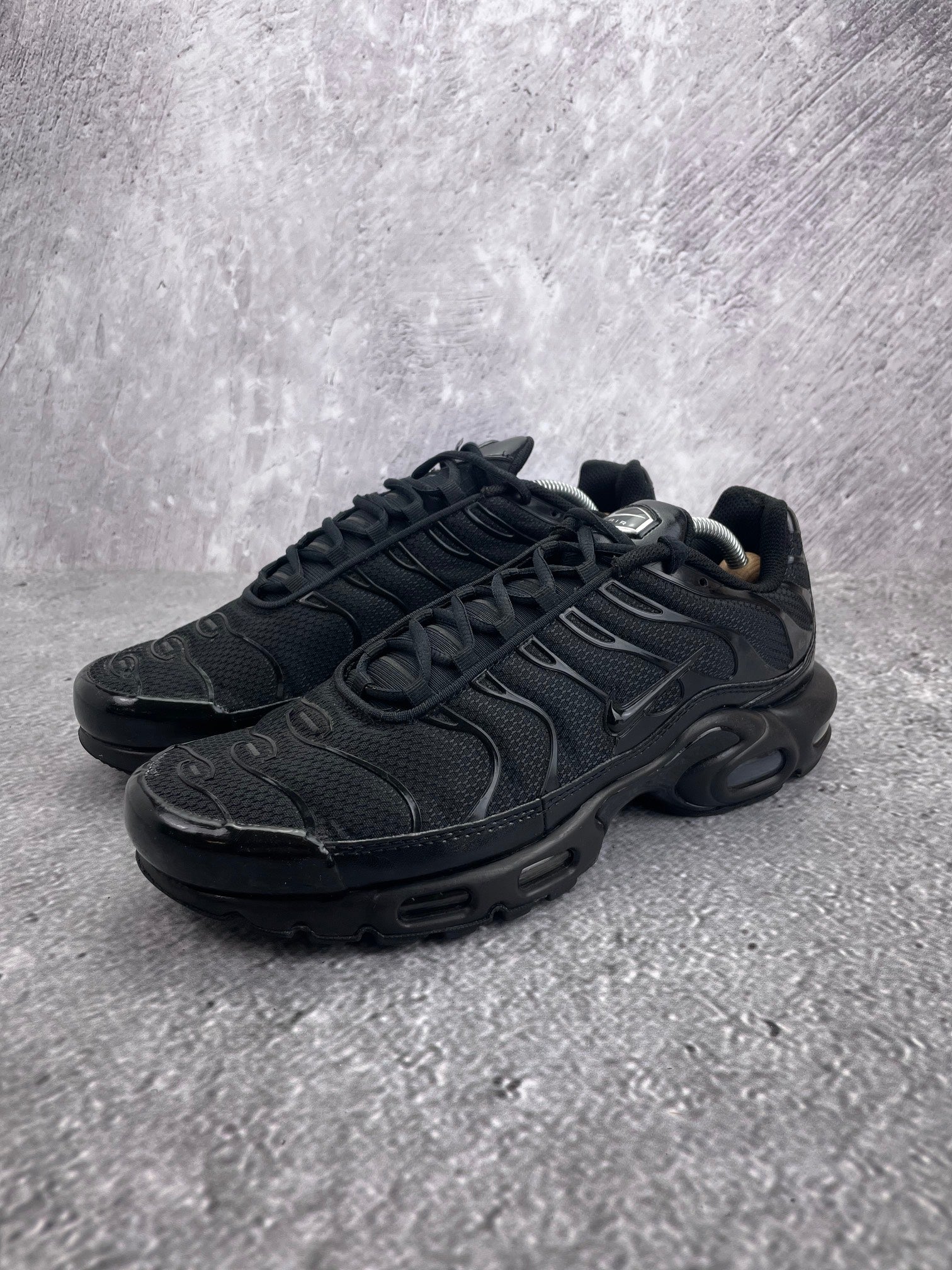 Nike Air Max Plus Triple Black - buty sportowe, widok z boku na tle studyjnym
