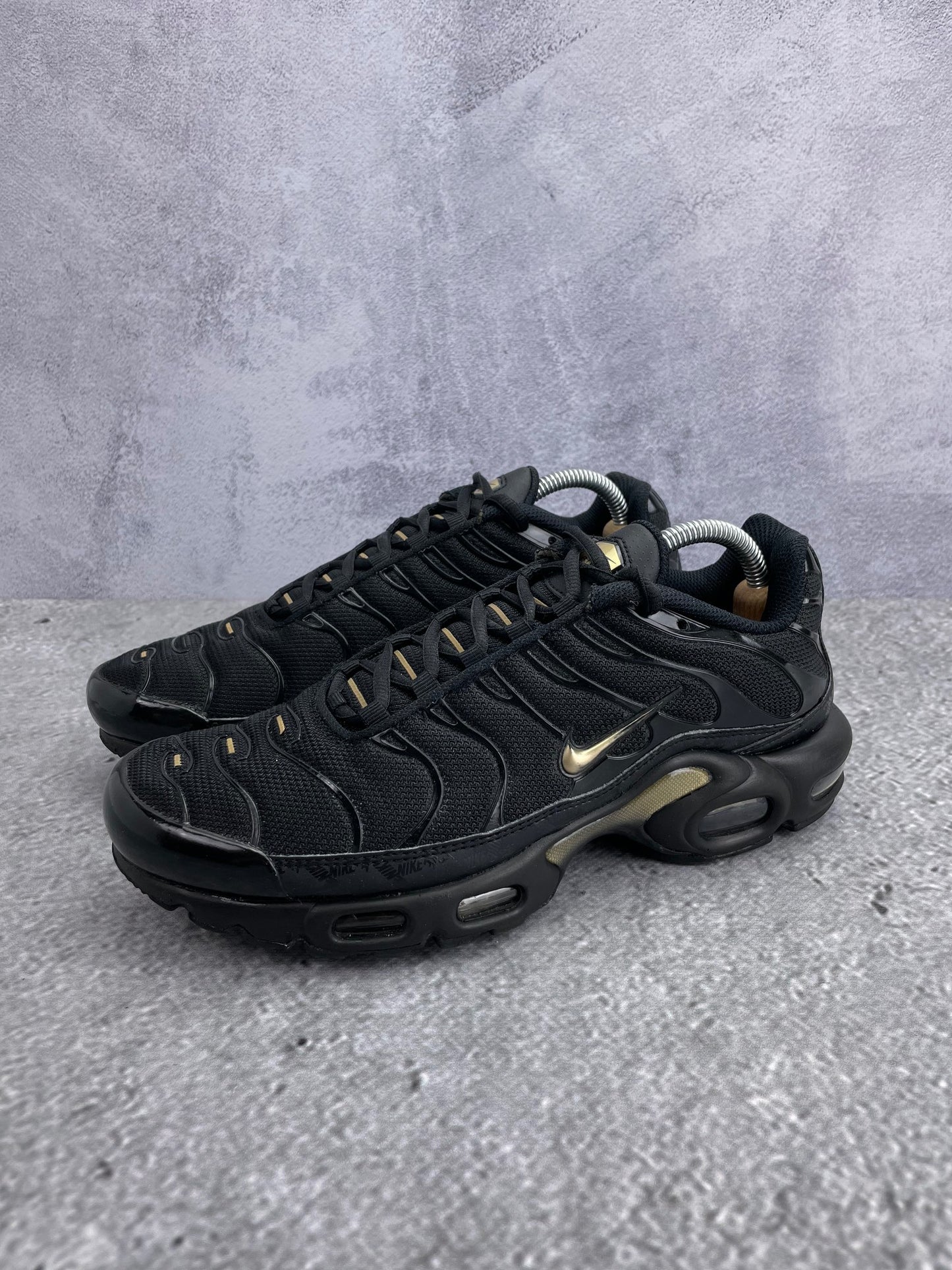 Nike Air Max Plus Black Metallic Gold - buty sportowe, widok z boku na tle studyjnym