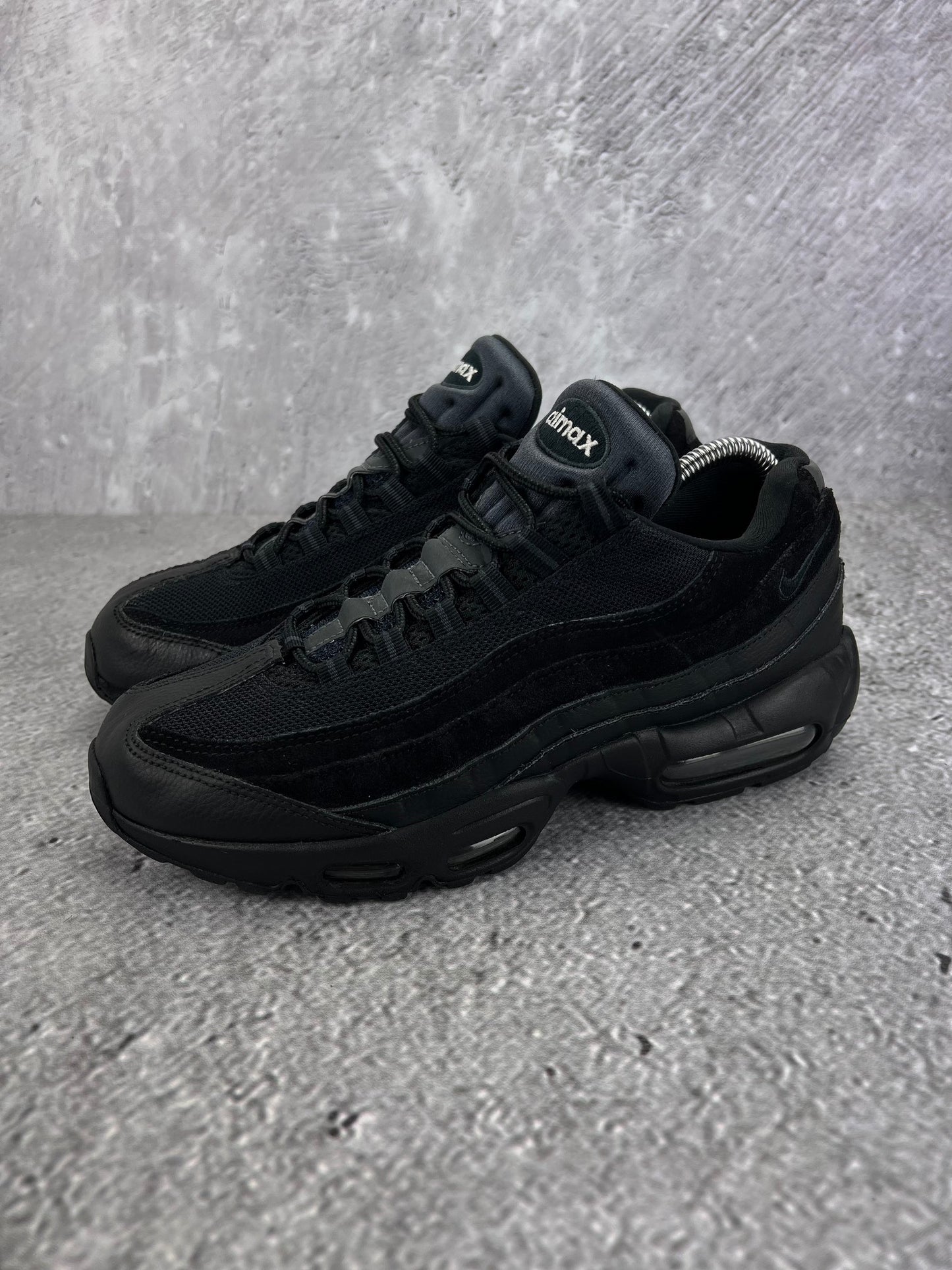 Nike Air Max 95 Essential Triple Black - buty sportowe, widok z boku na tle studyjnym