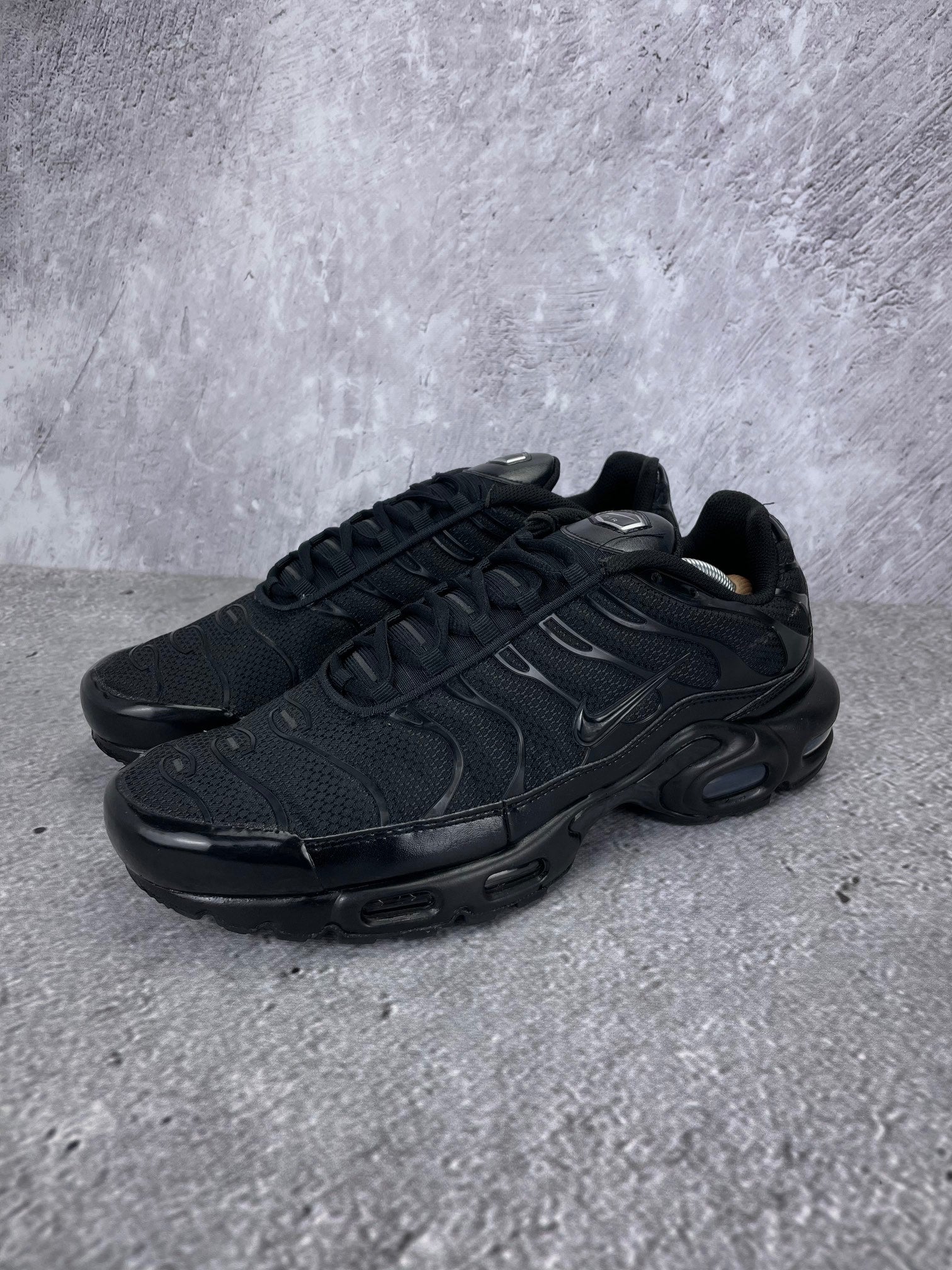 Nike Air Max Plus Triple Black - buty sportowe, widok z boku na tle studyjnym