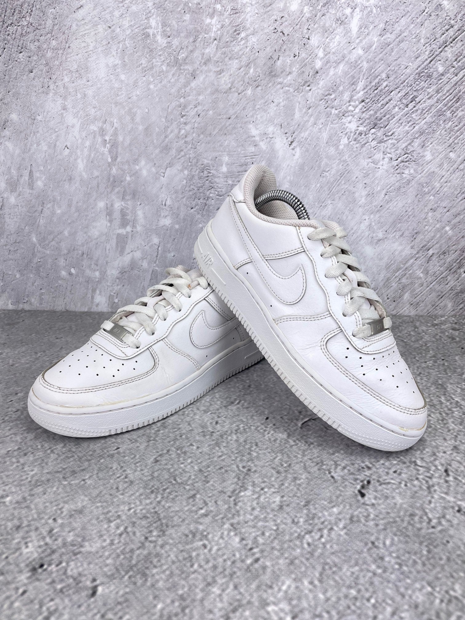 Nike Air Force 1 Low Triple White - buty sportowe, para butów, widok z boku na tle studyjnym